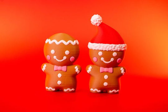 Gingerbread man novelty clickers with white icing-style details and pink bow ties on a red background
