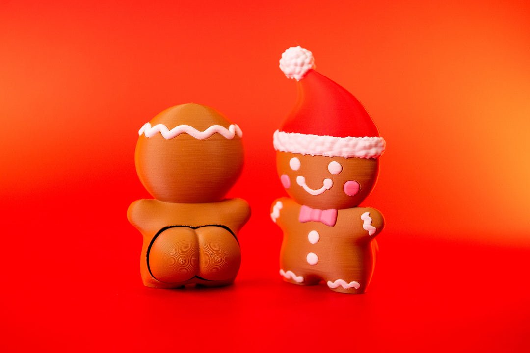 Front and rear views of gingerbread man Christmas clickers showing smiling face, pink bow tie and cheeky backside