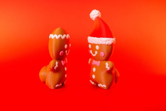Side views of gingerbread man clicker fidgets showing cheeky rear detail and Santa-hat design